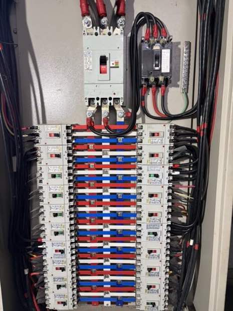 工廠電力配置施工現場:工業級大型動力盤內部,三相主無熔絲開關串接超過 20 組紅藍分支斷路器,主進線、各支路導線整齊配置。