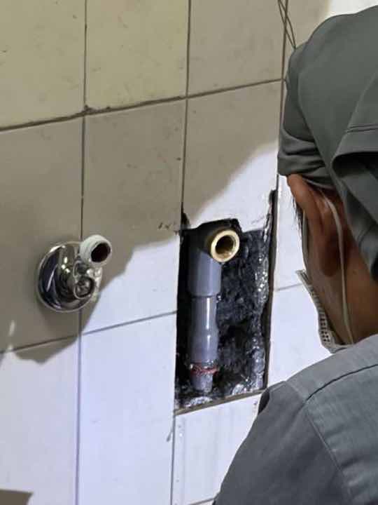 漏水查修：地磚切除後露出地下灰色 PVC 給水管與舊有金屬出水接頭，準備重接。