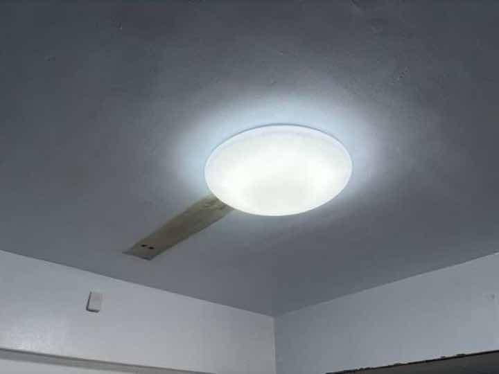設配安裝:天花板新裝大型圓形 LED 吸頂燈,旁可見木板補洞修補之配線通道。