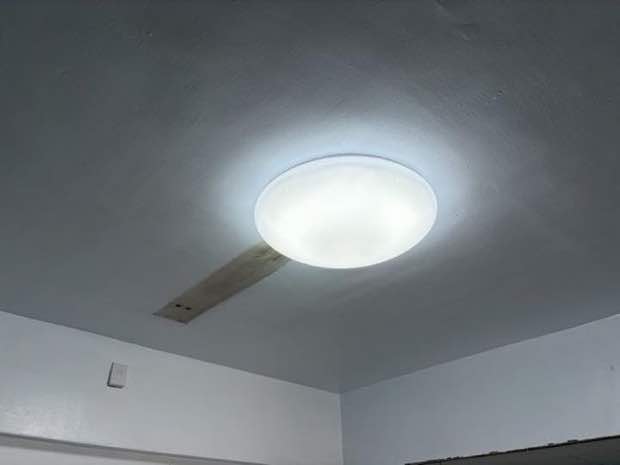 設配安裝:天花板新裝大型圓形 LED 吸頂燈,旁可見木板補洞修補之配線通道。